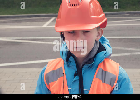 10 Jahre alten kaukasischen junge im Helm und Warnweste. Junger Ingenieur Konzept. Stockfoto