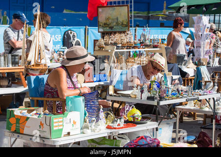 Frauen in Führungspositionen, Verkauf von Trödel und Antiquitäten auf einem Marktstand am Meer in Herne Bay, Kent. Andere Menschen sind die anderen Ständen surfen. Stockfoto