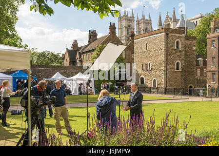 UK ein TV-Reporter spricht in die Kamera für eine News-Organisation an einem sonnigen Tag in London, in der Nähe Parlament und Palace of Westminster. Stockfoto