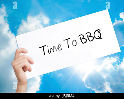Zeit zum BBQ Zeichen auf weißem Papier. Mann Hand Holding Papier mit dem Text. Auf Himmelshintergrund isoliert.  Technik, Internet-Konzept. Stockfoto