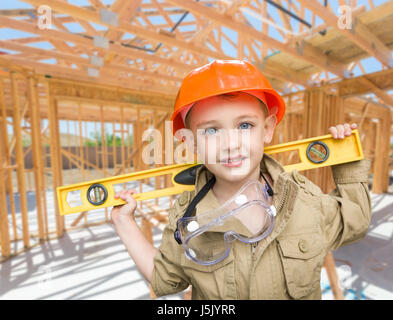 Junge Unternehmer mit Ebene vor Ort im neuen Hausbau-Framing. Stockfoto