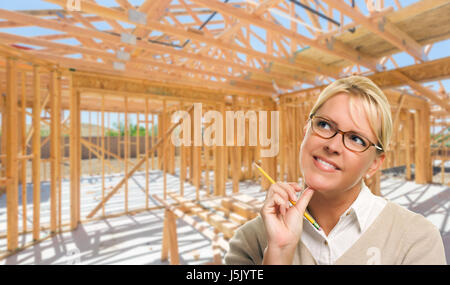 Nachdenkliche Frau mit Bleistift vor Ort im neuen Hausbau-Framing. Stockfoto