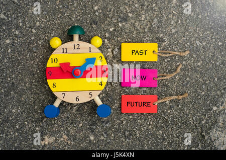 Wort Vergangenheit jetzt Zukunft auf bunte hölzerne Schild mit Uhr geschrieben. Stockfoto