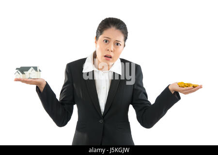 asiatische Bankmanager zeigt Haus und Münze Arme, Schultern zuckt mit den Schultern auf weißem Hintergrund. junge Mädchen auf der Suche habe Problem über das speichern. Stockfoto