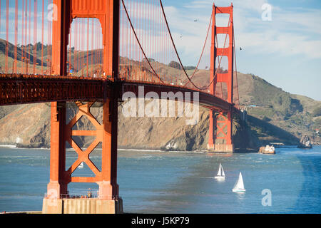 Sonnenuntergang ist auf dem Weg als Autos, Pedestrins, Boote, und Vögel bewegen sich die Golden Gate Bridge Stockfoto