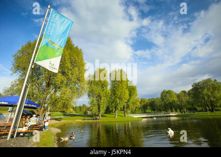 München, Deutschland - 6. Mai 2017: Ein Blick auf die Bäume und See mit Gänse und Schwäne im Olympiapark in München. Stockfoto