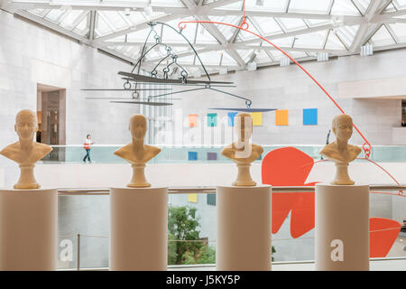 Atrium mit Frau zu Fuß und Kunst von Antoni, Kelly und Calder, National Gallery of Art, East Building, Washington, DC Stockfoto