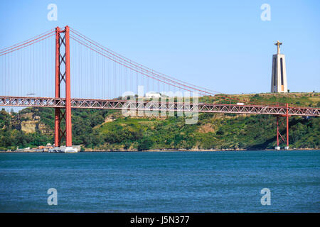 25. April Bridge Hängebrücke über den Fluss Tejo mit Jesus Christus-König-Statue auf Hintergrund in Lissabon, Portugal Stockfoto