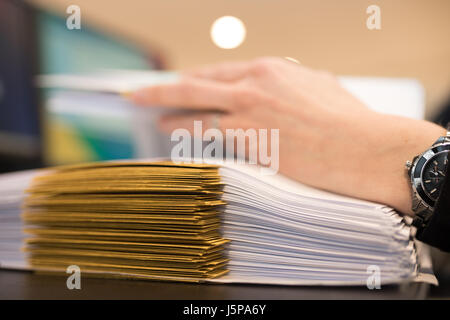 Nahaufnahme der weiblichen Hand mit Dossiers im Büro. Arbeiten auf einem Stapel von Dateien. Stockfoto