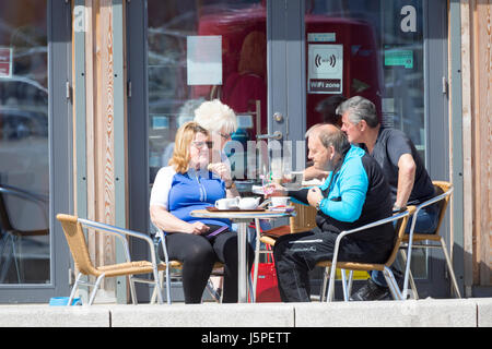 Denbighshire, Wales, UK Wetter - wärmere Wetter und Sonnenschein über der Nord Wales einschließlich dem Seebad Rhyl, Denbighshire. Die Menschen in der Sonne und Nachmittagstee vor einem Cafe auf der Promenade an der Küstenstadt Rhyl in Nord Wales Stockfoto