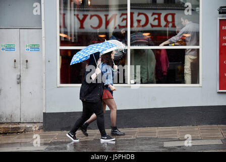 Brighton, UK. 18. Mai 2017. Junge Frauen spiegelt sich in einem Fenster, wie sie in sintflutartigen Regen durch Zentrum von Brighton Fuß heute Credit: Simon Dack/Alamy Live News Stockfoto