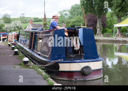 Schüren Sie Bruerne, Northamptonshire, 18. Mai 2017. Ein Mann saß auf dem Heck ein Longboat spielen seine Saiteninstrumente (eine kleine Mandoline) an einem warmen Nachmittag am Grand Union Canal. Bildnachweis: Keith J Smith. / Alamy Live News Stockfoto