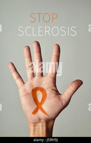 der Text Stop Sklerose und eine orange Band auf die Handfläche eines jungen Mannes gemalt Stockfoto