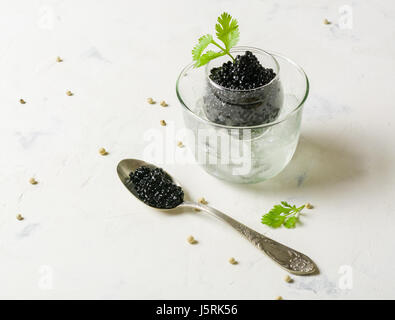 Schwarzer Kaviar in einer Glasschale mit Eis. Silber-Löffel und weißem Hintergrund. Platz für den Text. Stockfoto