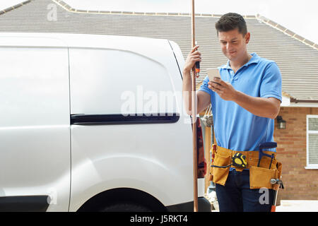 Klempner mit Van mit Handy vor Haus Stockfoto