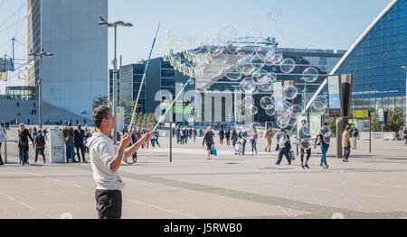 Nanterre, Frankreich - 9. Mai 2017: Macht ein Mann, beobachtet von Passanten, riesige Seifenblasen mitten auf dem zentralen Platz der Verteidigung, der große moderne Stockfoto