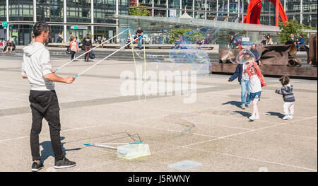Nanterre, Frankreich - 9. Mai 2017: Macht ein Mann, beobachtet von Passanten, riesige Seifenblasen mitten auf dem zentralen Platz der Verteidigung, der große moderne Stockfoto
