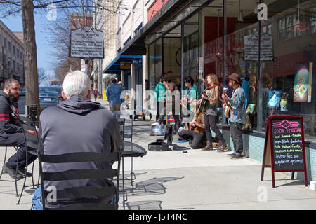 Asheville, North Carolina, USA - 24. März 2017: Menschen sitzen im Freien Tische auf der Straße als Straßenmusiker Musik für Tipps vor der historischen spielen Stockfoto