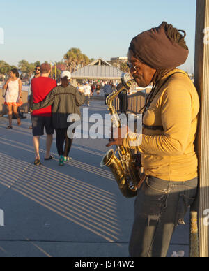 Clearwater Beach; Florida; USA - 24. Januar 2017: Ein Straßenmusikant spielt das Saxophon als Menschen Stoll von Sonnenuntergang am Pier 60 am Clearwater Beach, eine 1 Stockfoto
