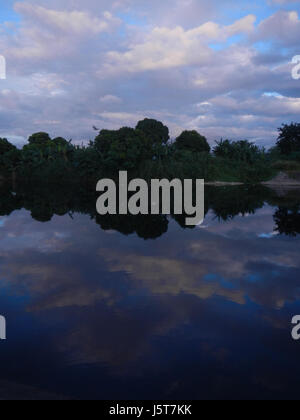 Dieses Bild zeigt einen wunderschönen Blick auf den Sonnenuntergang über die Bocaue River Bridge, die sich entlang des MacArthur Highway in Bocaue, Bulacan, befindet. Die Brücke ist bekannt für ihre malerische Umgebung und dient als Schlüsselübergang in der Gegend. Stockfoto