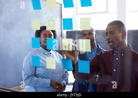 Afrikanische Unternehmer brainstorming mit Haftnotizen auf eine Glaswand Stockfoto