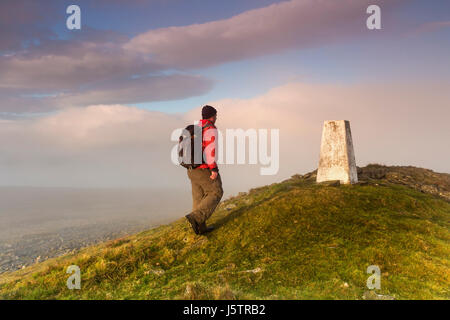 Wanderer zu Fuß auf den Gipfel Trig Punkt des großen steinigen Hügel, wie der Nebel lichtet, obere Teesdale, County Durham, Großbritannien Stockfoto