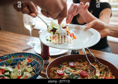Nahaufnahme von Menschen Essen auf den Teller setzen und Abendessen zusammen mit Stockfoto