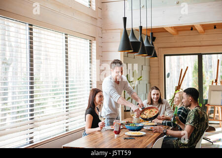 Gruppe von fröhlichen jungen Leuten Pasta Essen und plaudern in der Küche Stockfoto
