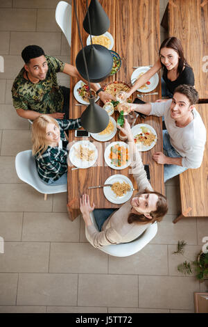 Draufsicht der fünf Menschen jubeln mit Wein am rustikalen Esstisch sitzen und blickte in die Kamera Stockfoto
