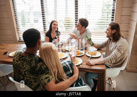 Gruppe von lächelnden jungen Leuten Essen und sprechen in der Küche zu Hause Stockfoto