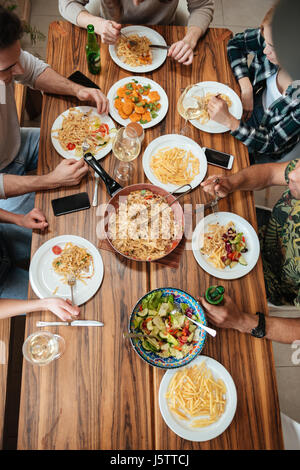 Draufsicht der Gruppe von Menschen, die Abendessen zusammen sitzend am rustikalen Holztisch zu Hause Stockfoto