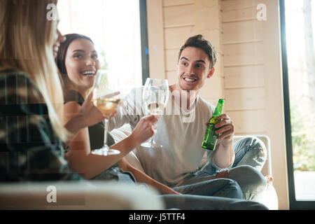 Gruppe von fröhlichen jungen Freunden trinken Wein und Bier auf dem Sofa zu Hause Stockfoto