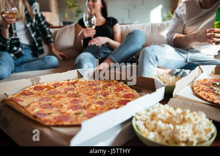 Gruppe von fröhlichen jungen Menschen Pizza essen, trinken Wein und Bier auf dem Sofa zu Hause Stockfoto