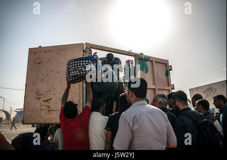 Eine Gruppe von vertriebenen Flüchtlingen Klettern auf einen LKW zu Hammam al Alil Verschiebung Camp, Irak Stockfoto