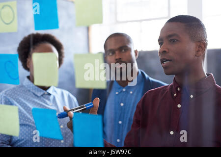 Afrikanischen Kollegen Strategieentwicklung mit Haftnotizen auf eine Glaswand Stockfoto