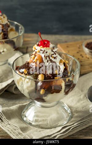 Süße hausgemachte Eisbecher mit Schokosauce Peantus und Kirsche Stockfoto