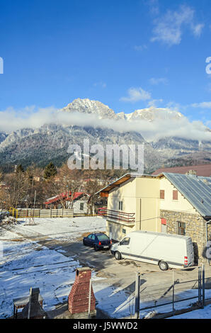 Karpaten Blick vom Busteni Stadt, Bucegi mit Kreuz in Spitze des Caraiman Peak, Wolken, Schnee und Nebel, Zeit Winterlandschaft. Stockfoto