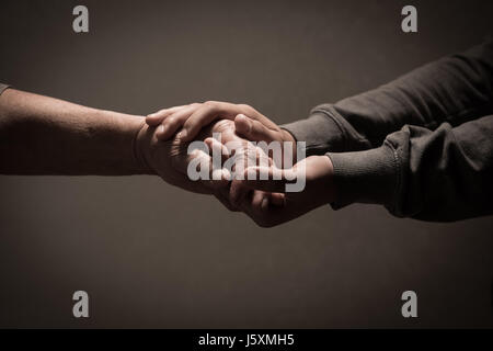 Kind die Hände halten senior Frauenhand auf braunem Hintergrund, Frankreich Stockfoto