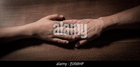 Kind die Hände halten senior Frauenhand auf braunem Hintergrund, Frankreich Stockfoto