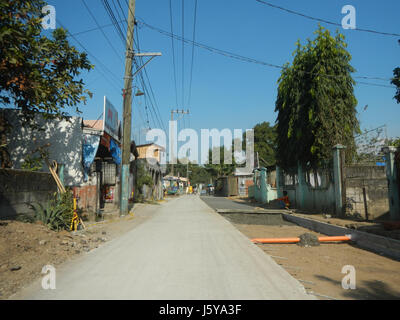 Das Bild zeigt eine Ansicht der Lagundi Sipat Dampol, einer Region in Plaridel, Bulacan, die die ländliche Landschaft mit einem Schwerpunkt auf der Landwirtschaftsstraße zeigt. Die Szene repräsentiert die landwirtschaftlichen Aktivitäten, die typisch für Bulacans Landwirtschaftsgemeinden sind. Stockfoto