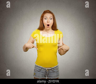 Porträt überraschte junge glückliche Frau stehend auf leere textfreiraum von ihrem gelben T-shirt isoliert graue Wand Hintergrund zeigen. Positive menschliche emotion Stockfoto