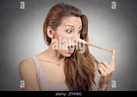 Frau mit langen Nase auf graue Wand Hintergrund isoliert. Lügner-Konzept. Menschlichen Gesichtsausdruck, Emotionen, Gefühle. Stockfoto