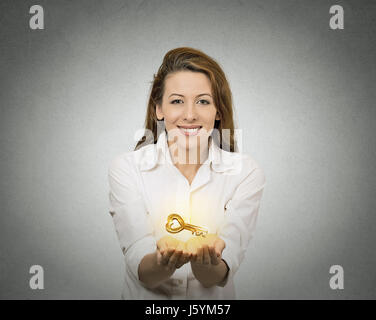 Glückliche Frau Porträt, Hände halten, bietet neue Schlüssel zum Erfolg isoliert graue Wand Background. Positive Emotionen, Gesichtsausdruck. Erfolgreiche ca Stockfoto