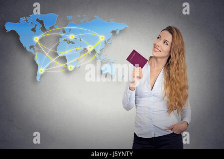 Porträt happy Tourist junge Frau mit Reisepass stehend betrachten Welt Kartenhintergrund Planung isolierte graue Wand. Positive menschliche Emotion Gesicht Stockfoto