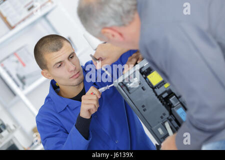 Lehrling arbeitet an Elektrogerät Stockfoto