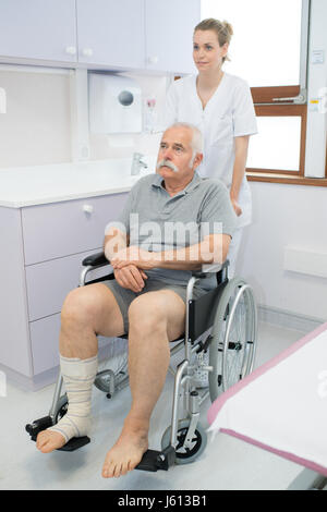 Krankenschwester drängen senior Mann im Rollstuhl Stockfoto