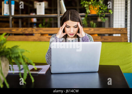 Junge Frau, die Arbeiten am Schreibtisch vor Laptop leiden unter chronischen täglichen Kopfschmerzen Stockfoto