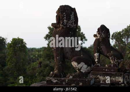 Zwei steinerne Statuen der Löwen beobachten Sie den Sonnenuntergang im Prei Rup Tempel, Angkor Wat Stockfoto