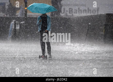 München, Deutschland. 19. Mai 2017. Eine Mädchen mit einem Roller fährt durch ein Hagelsturm in München, 19. Mai 2017. Foto: Matthias Balk/Dpa/Alamy Live News Stockfoto
