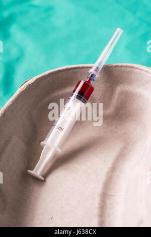 Medizinische Spritze mit Bloodsample liegen in einer Kapsel eine Verwendung auf grünem Hintergrund des Krankenhauses. Der Hintergrund kann eine Textile gehören eines Arztes oder nu Stockfoto